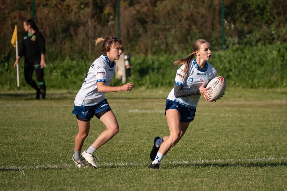 Dwie zawodniczki rugby w&nbsp;białych strojach rozpoczynają akcję ataku