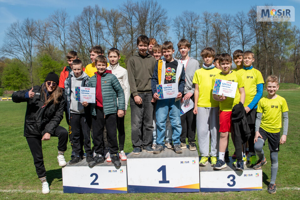 Grupa uczniów na&nbsp;podium z&nbsp;dyplomami za zajęcie pierwszego, drugiego i&nbsp;trzeciego miejsca w&nbsp;zawodach szkół podstawowych.