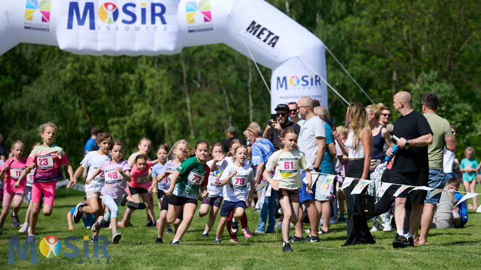 Dzieci biegnące w&nbsp;zawodach sportowych pod dmuchaną bramą z&nbsp;napisem META i&nbsp;logo MOSiR Mysłowice.